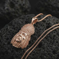 Load image into Gallery viewer, Rose gold plated feather headdress chief pendant necklace on textured volcanic rock, detailed macro product shot with soft warm reflections and bold heritage-style symbolism.