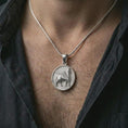 Load image into Gallery viewer, Polished silver Assyrian Lamassu pendant necklace worn on the chest, masculine lifestyle shot highlighting the winged bull relief and bright silver finish.