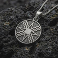 Load image into Gallery viewer, Oxidized Assyrian Lamassu backside of the pendant on textured volcanic rock, close-up studio shot highlighting the Assyrian Sun, ancient relief details, and antique silver contrast.