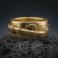 Load image into Gallery viewer, Gold plated Bushido sword band ring on textured volcanic rock, premium close-up studio composition emphasizing the katana-style sword, warrior symbolism, and engraved band texture.