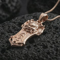 Load image into Gallery viewer, A rose gold plated Taurus bull pendant is photographed on porous volcanic rock in a close-up studio composition with refined luxury lighting.