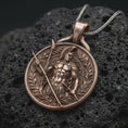Load image into Gallery viewer, A Bronze Spartan warrior pendant rests on dark volcanic rock in a macro studio close-up, showing a detailed Greek soldier with spear and laurel frame.