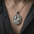Load image into Gallery viewer, A polished silver Gemini pendant is worn on the neck in a premium close-up lifestyle image, showing the two facing figures clearly.