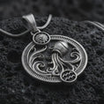 Load image into Gallery viewer, Oxidized Aquarius zodiac pendant necklace on textured volcanic rock, close-up studio shot highlighting the water bearer vessel, flowing waves, sun detail, and antique silver contrast.