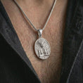 Load image into Gallery viewer, A polished silver Aztec mask pendant is worn on the neck in a premium close-up lifestyle image, showing the detailed tribal mask motif clearly.