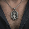 Load image into Gallery viewer, Oxidized serpent and anchor pendant necklace worn on the chest, close-up lifestyle jewelry photo showing the nautical amulet on a spiga chain with dark clothing.