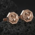 Load image into Gallery viewer, Rose gold plated scarab cufflinks are photographed on porous volcanic rock in a close-up studio composition with refined luxury lighting and bold ancient detail.