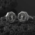Load image into Gallery viewer, An oxidized Yggdrasil cufflink pair rests on dark volcanic rock in a macro studio close-up, showing a woven Tree of Life design inside octagon frames.