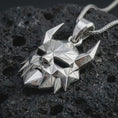 Load image into Gallery viewer, A polished silver Surtur pendant is displayed on black volcanic rock in a premium macro studio close-up with geometric planes and a bold fire giant design.