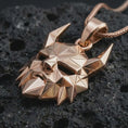 Load image into Gallery viewer, A rose gold plated Surtur pendant is photographed on porous volcanic rock in a close-up studio composition with refined luxury lighting and faceted sculptural detail.