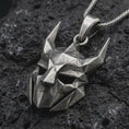 Load image into Gallery viewer, An oxidized Loki pendant rests on dark volcanic rock in a macro studio close-up, showing a faceted horned mask inspired by Norse mythology.