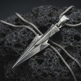 Load image into Gallery viewer, An oxidized Gungnir pendant rests on dark volcanic rock in a macro studio close-up, showing Odin’s spear in a sharp geometric Norse design.