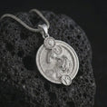 Load image into Gallery viewer, Polished silver Aries zodiac pendant necklace on textured volcanic rock, centered macro jewelry photo with detailed ram horoscope relief and bright silver highlights.