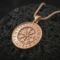 Load image into Gallery viewer, Rose gold plated Vegvisir Viking rune pendant necklace on textured volcanic rock, detailed macro product shot with soft warm reflections and symbolic Norse talisman styling.