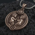 Load image into Gallery viewer, Bronze Gemini zodiac pendant necklace on textured volcanic rock, close-up studio shot highlighting the twin figures, sun detail, Gemini symbol, and antique silver contrast.