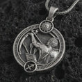 Load image into Gallery viewer, Oxidized Sagittarius zodiac pendant necklace on textured volcanic rock, close-up studio shot highlighting the archer figure, bow and arrow, sun detail, and antique silver contrast.