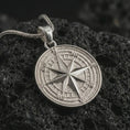 Load image into Gallery viewer, Polished silver compass rose pendant necklace on textured volcanic rock, centered macro jewelry photo with detailed navigation markings and bright silver highlights.