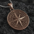 Load image into Gallery viewer, Bronze compass rose pendant necklace on textured volcanic rock, close-up studio shot highlighting the raised directional star, cardinal letters, circular map dial, and antique silver contrast.