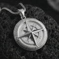 Load image into Gallery viewer, Polished silver compass pendant necklace on textured volcanic rock, centered macro jewelry photo with detailed navigation markings, sharp star relief, and bright silver highlights.