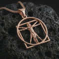 Load image into Gallery viewer, Rose gold plated Vitruvian Man pendant necklace on textured volcanic rock, detailed macro product shot with soft warm reflections and artistic anatomical styling.