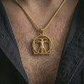 Load image into Gallery viewer, Gold plated Vitruvian Man pendant necklace worn on the chest, premium lifestyle jewelry photo with the Renaissance anatomy pendant centered on a spiga chain.
