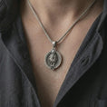 Load image into Gallery viewer, Oxidized Leo zodiac pendant necklace worn on the chest, close-up lifestyle jewelry photo showing the lion astrology medallion on a spiga chain with dark clothing.
