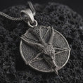 Load image into Gallery viewer, Oxidized goat pentagram pendant necklace on textured volcanic rock, close-up studio shot highlighting the horned goat head, five-point star, textured medallion base, and antique silver contrast.