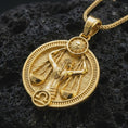 Load image into Gallery viewer, Gold plated Libra zodiac pendant necklace on textured volcanic rock, premium close-up studio composition emphasizing the balance scales, sun motif, and astrology medallion design.