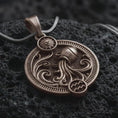 Load image into Gallery viewer, Bronze Aquarius zodiac pendant necklace on textured volcanic rock, close-up studio shot highlighting the water bearer vessel, flowing waves, sun detail, and antique silver contrast.