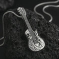 Load image into Gallery viewer, Polished silver skull guitar pendant necklace on textured volcanic rock, centered macro jewelry photo with detailed gothic musician relief and bright silver highlights.