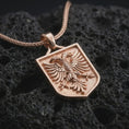 Load image into Gallery viewer, Rose gold plated double-headed eagle shield pendant necklace on textured volcanic rock, detailed macro product shot with soft warm reflections and symbolic Balkan eagle styling.