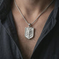 Load image into Gallery viewer, Polished silver double-headed eagle shield pendant necklace worn on the chest, masculine lifestyle shot highlighting the twin eagle relief, shield frame, and bright silver finish.