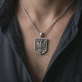 Load image into Gallery viewer, Oxidized double-headed eagle shield pendant necklace worn on the chest, close-up lifestyle jewelry photo showing the Albanian eagle crest on a spiga chain with dark clothing.