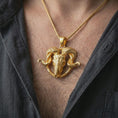 Load image into Gallery viewer, Gold plated ram skull pendant necklace worn on the chest, premium lifestyle jewelry photo with the Viking-inspired ram skull pendant centered on a spiga chain.