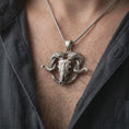 Load image into Gallery viewer, Oxidized ram skull pendant necklace worn on the chest, close-up lifestyle jewelry photo showing the gothic animal skull pendant on a spiga chain with dark clothing.