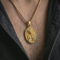 Load image into Gallery viewer, A gold plated Aztec mask pendant is worn on the neck in a close-up lifestyle shot, styled as a meaningful ancient warrior amulet for men.