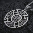 Load image into Gallery viewer, Oxidized Celtic cross pendant necklace on textured volcanic rock, close-up studio shot highlighting the circular cross shape, Norse knotwork pattern, openwork details, and antique silver contrast.