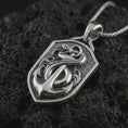 Load image into Gallery viewer, Polished silver serpent and anchor pendant necklace on textured volcanic rock, centered macro jewelry photo with detailed maritime relief and bright silver highlights.