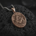 Load image into Gallery viewer, Bronze Masonic square and compass pendant necklace on textured volcanic rock, close-up studio shot highlighting the Freemason symbol, ornate border, engraved details, and antique silver contrast.
