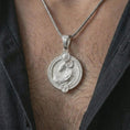 Load image into Gallery viewer, Polished silver Aries zodiac pendant necklace worn on the chest, masculine lifestyle shot highlighting the ram relief, sun detail, and bright silver finish.