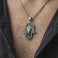 Load image into Gallery viewer, Oxidized hamsa elephant pendant necklace worn on the chest, close-up lifestyle jewelry photo showing the protective elephant amulet on a spiga chain with dark clothing.
