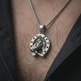 Load image into Gallery viewer, Oxidized horseshoe pendant necklace worn on the chest, close-up lifestyle jewelry photo showing the lucky horse charm on a spiga chain with dark clothing.