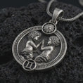 Load image into Gallery viewer, Oxidized Gemini zodiac pendant necklace on textured volcanic rock, close-up studio shot highlighting the twin figures, sun detail, Gemini symbol, and antique silver contrast.