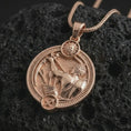 Load image into Gallery viewer, Rose gold plated Sagittarius zodiac pendant necklace on textured volcanic rock, detailed macro product shot with soft warm reflections and symbolic zodiac styling.