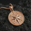 Load image into Gallery viewer, Rose gold plated compass rose pendant necklace on textured volcanic rock, detailed macro product shot with soft warm reflections and symbolic journey-inspired styling.