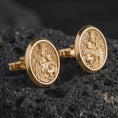 Load image into Gallery viewer, Gold plated Blessed Mother cufflinks sit on textured volcanic rock in a dramatic studio macro shot, highlighting the sacred Virgin Mary and Child design.