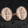 Load image into Gallery viewer, Rose gold plated St Dominic cufflinks are photographed on porous volcanic rock in a close-up studio composition with refined luxury lighting and religious detail.