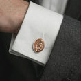 Load image into Gallery viewer, A rose gold plated Pensive Christ cufflink is worn on a shirt cuff in a close-up lifestyle composition, highlighting its oval frame and sacred Christ design.