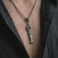 Load image into Gallery viewer, An oxidized demon slayer sword pendant is worn on the neck in a close-up lifestyle shot, centered on the chest as a dark fantasy warrior necklace.