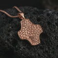 Load image into Gallery viewer, A rose gold plated Tree of Life cross pendant is photographed on porous volcanic rock in a close-up studio composition with refined luxury lighting and botanical detail.